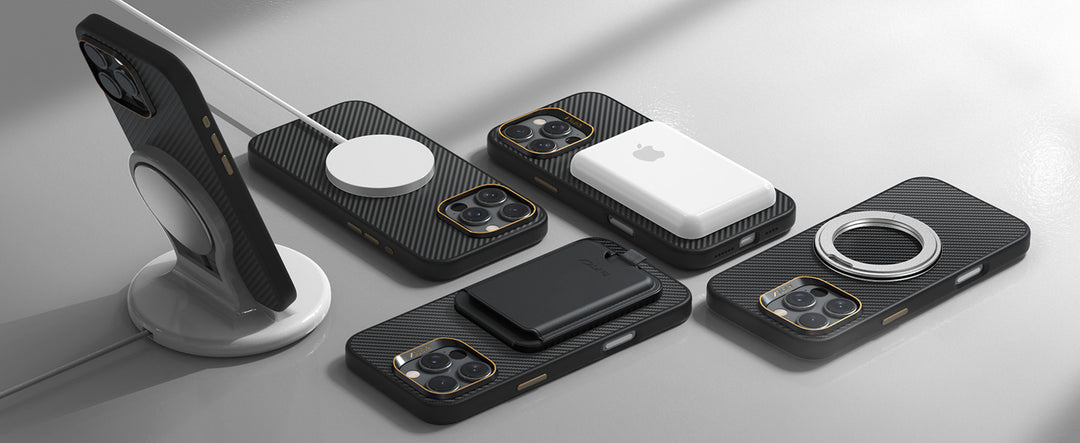 Five black, carbon-fiber patterned iPhones with modular magnetic accessories—chargers, stands, and wallets—are displayed on a light gray surface with soft shadows, highlighting sleek, modern design.