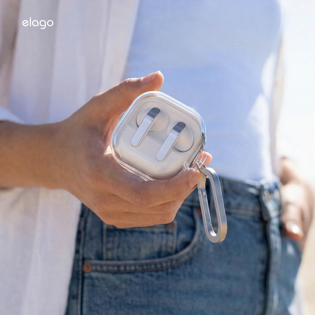 A person in blue jeans and a white top holds the MobileTechnica Samsung Galaxy Buds 4 Pro & Buds 4 Case, a premium clear cover with wireless charging and silver carabiner. The softly lit image highlights the case in use.