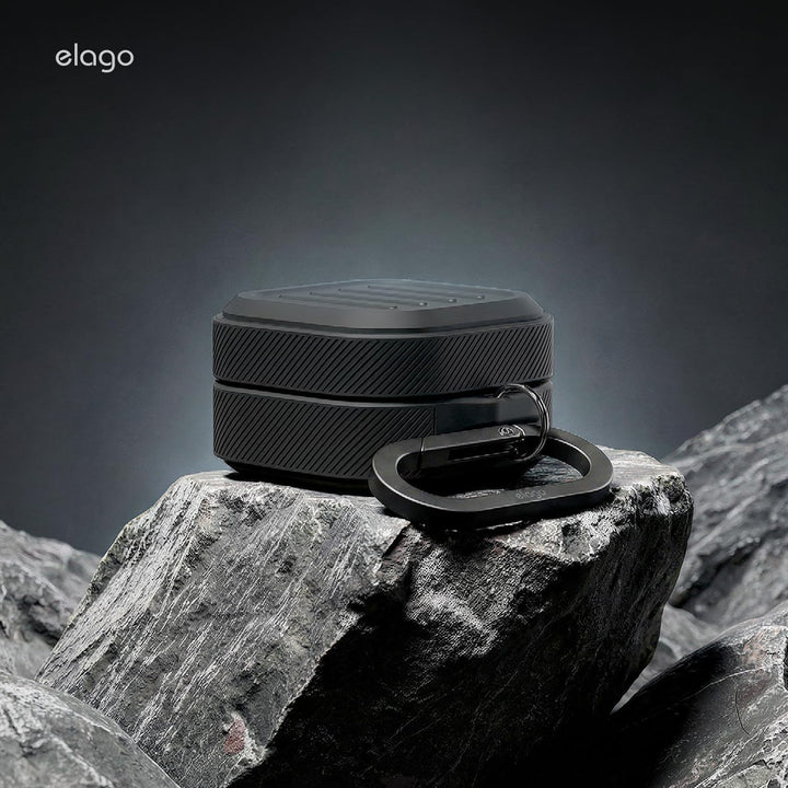 A premium black silicone case for Samsung Galaxy Buds 4 Pro by MobileTechnica, with a hexagonal textured design and matching carabiner, sits on rugged gray rock under dramatic lighting. Wireless charging supported.