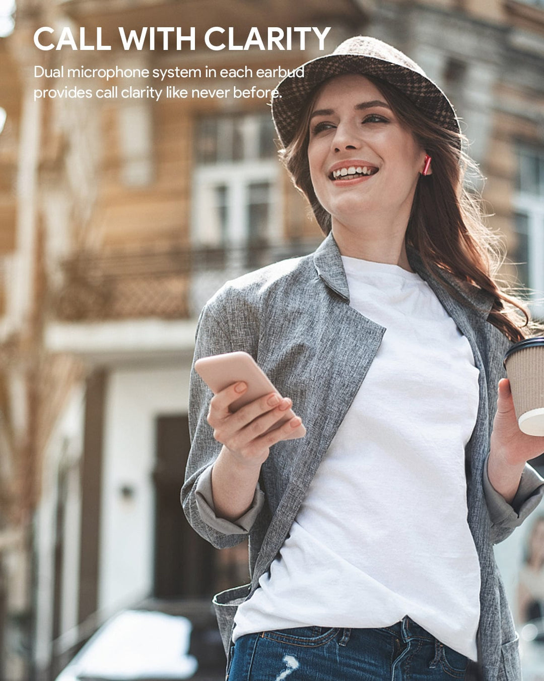 A young woman wearing a gray jacket, white T-shirt, and hat smiles outdoors holding a smartphone and coffee cup. She wears Aukey MiniNC wireless earbuds. White text reads: "CALL WITH CLARITY – Enjoy crystal-clear calls with dual mics in every earbud.