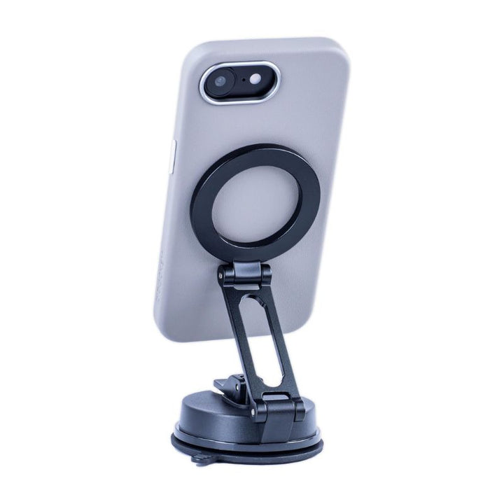 An iPhone 16e in a Dockem Apex MagSafe gray synthetic leather case is secured upright and tilted on a black adjustable phone holder with a suction cup, gripping the device via its magnetic ring.