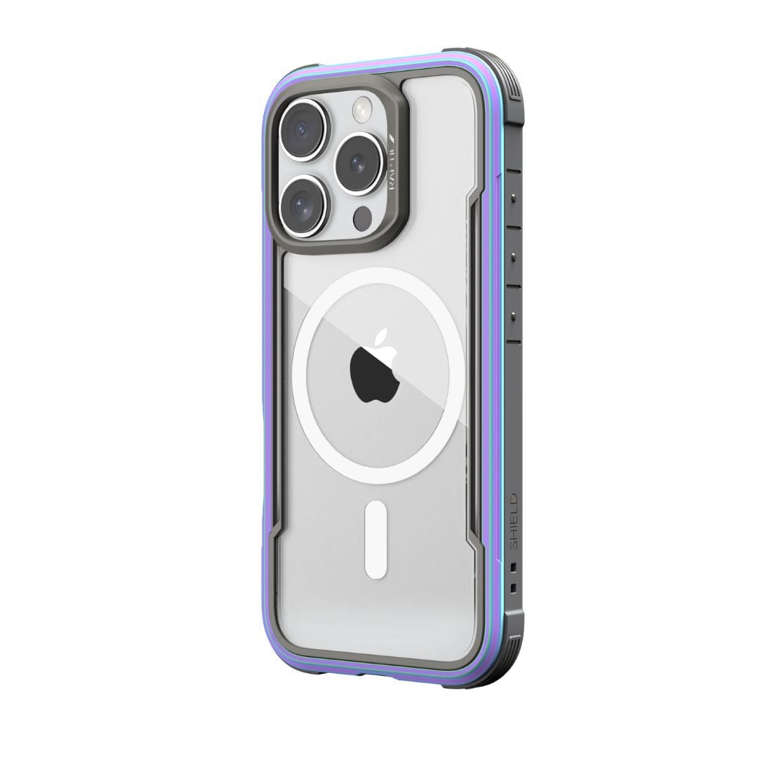 A smartphone in a rugged, transparent case with a purple and blue bumper. The Raptic Shield MagSafe Case for iPhone 16 Pro features three prominent camera lenses arranged in a triangle and the Apple logo on the back. The case, boasting "SHIELD" branding on the side, offers drop protection and is wireless charging compatible.