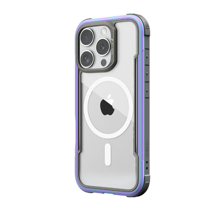 A smartphone in a rugged, transparent case with a purple and blue bumper. The Raptic Shield MagSafe Case for iPhone 16 Pro features three prominent camera lenses arranged in a triangle and the Apple logo on the back. The case, boasting "SHIELD" branding on the side, offers drop protection and is wireless charging compatible.